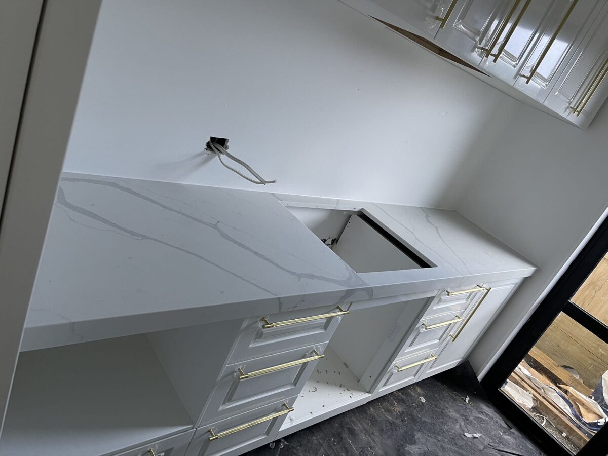 Modern kitchen installation with white cabinets and marble countertops.