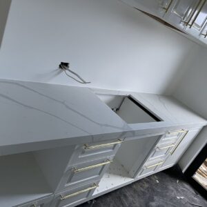 Modern kitchen installation with white cabinets and marble countertops.