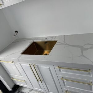 White kitchen countertop with gold sink and handles.
