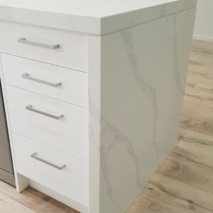 White marble kitchen island with drawers and silver handles.