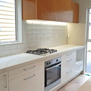 Modern kitchen with marble countertop and wooden cabinets.