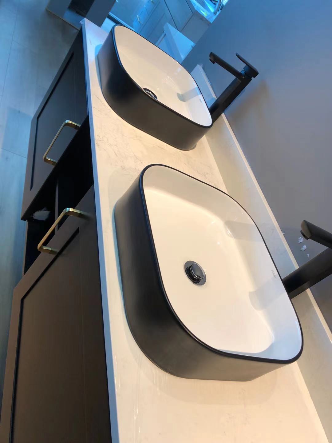 Modern black and white bathroom sinks on marble countertop.