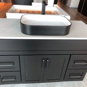 Black bathroom vanity with white countertop and rectangular sink.