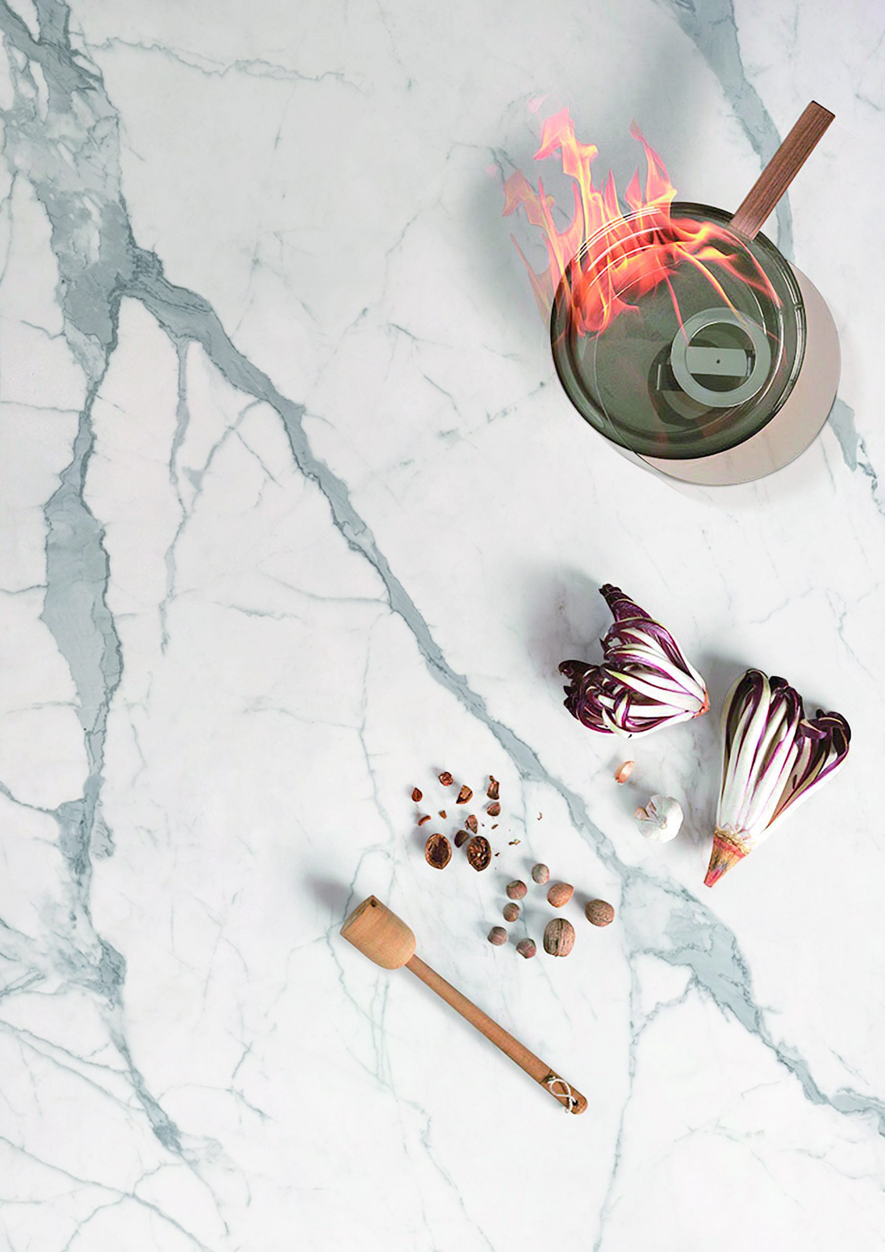 Marble countertop with vegetables, spices, and a flaming pot.