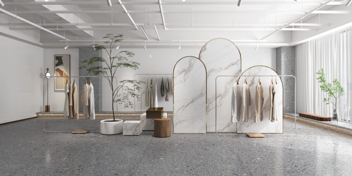Minimalist clothing store interior with marble dividers and hanging garments.